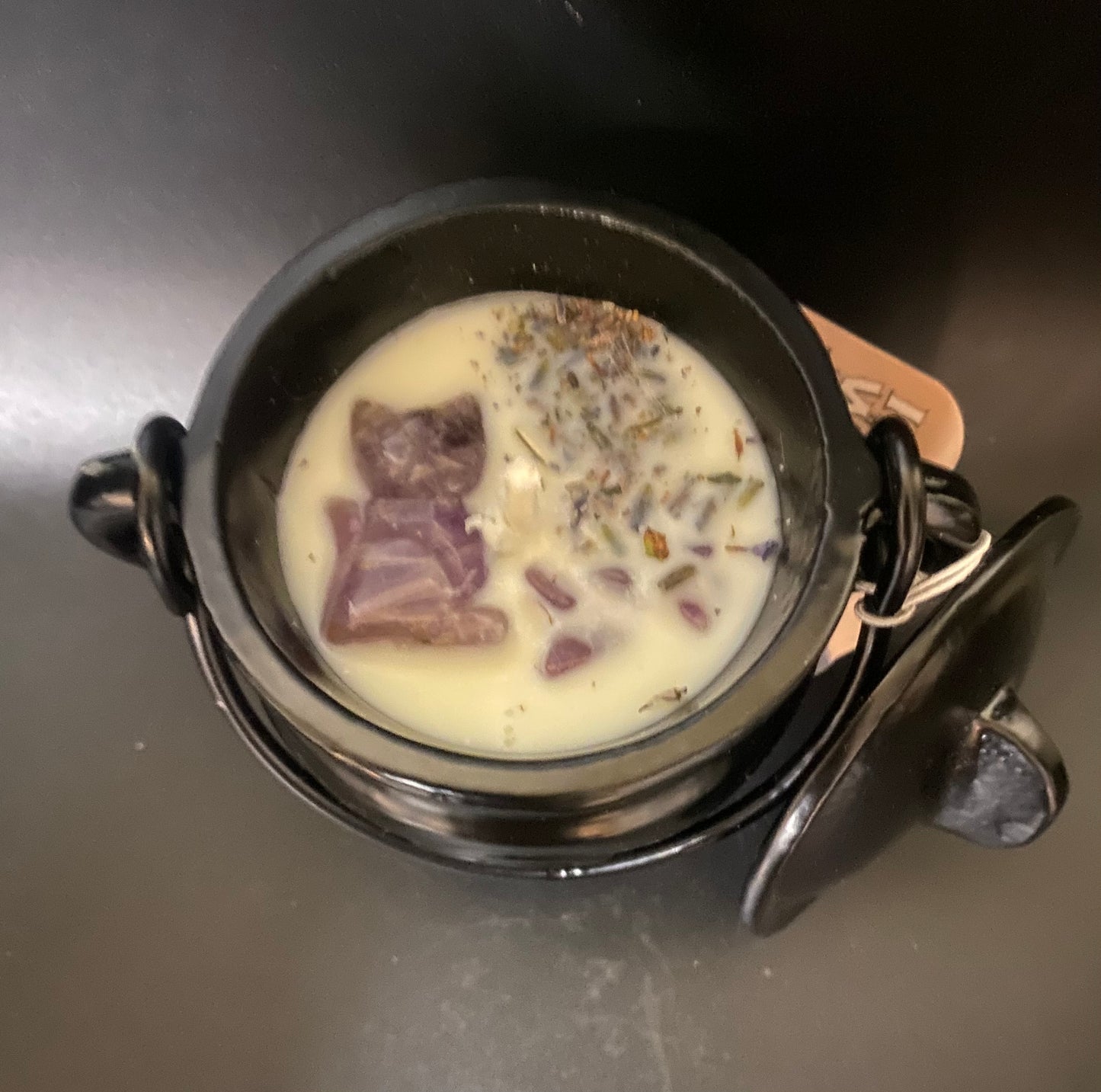 Black cauldron candle and purple stones on a dark surface