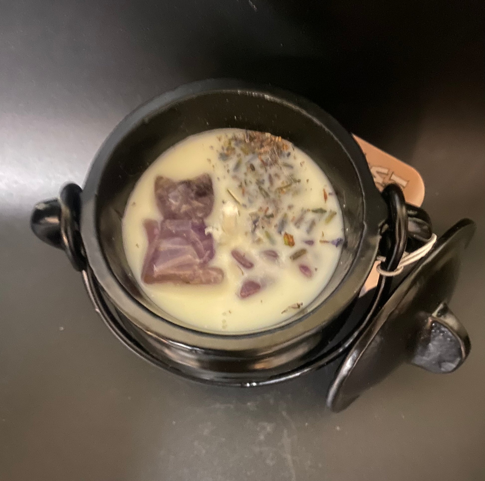 Black cauldron candle and purple stones on a dark surface