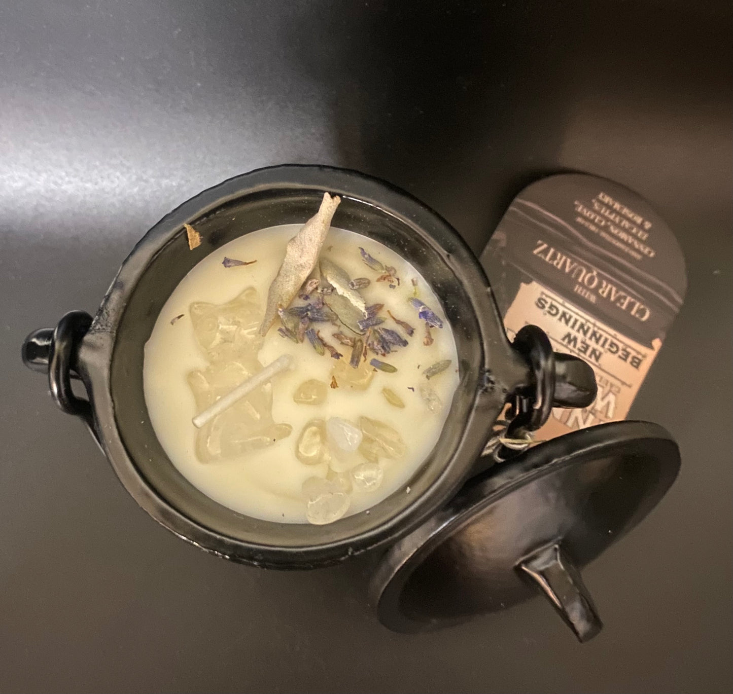 Candle with lavender buds in a cauldron on a dark surface