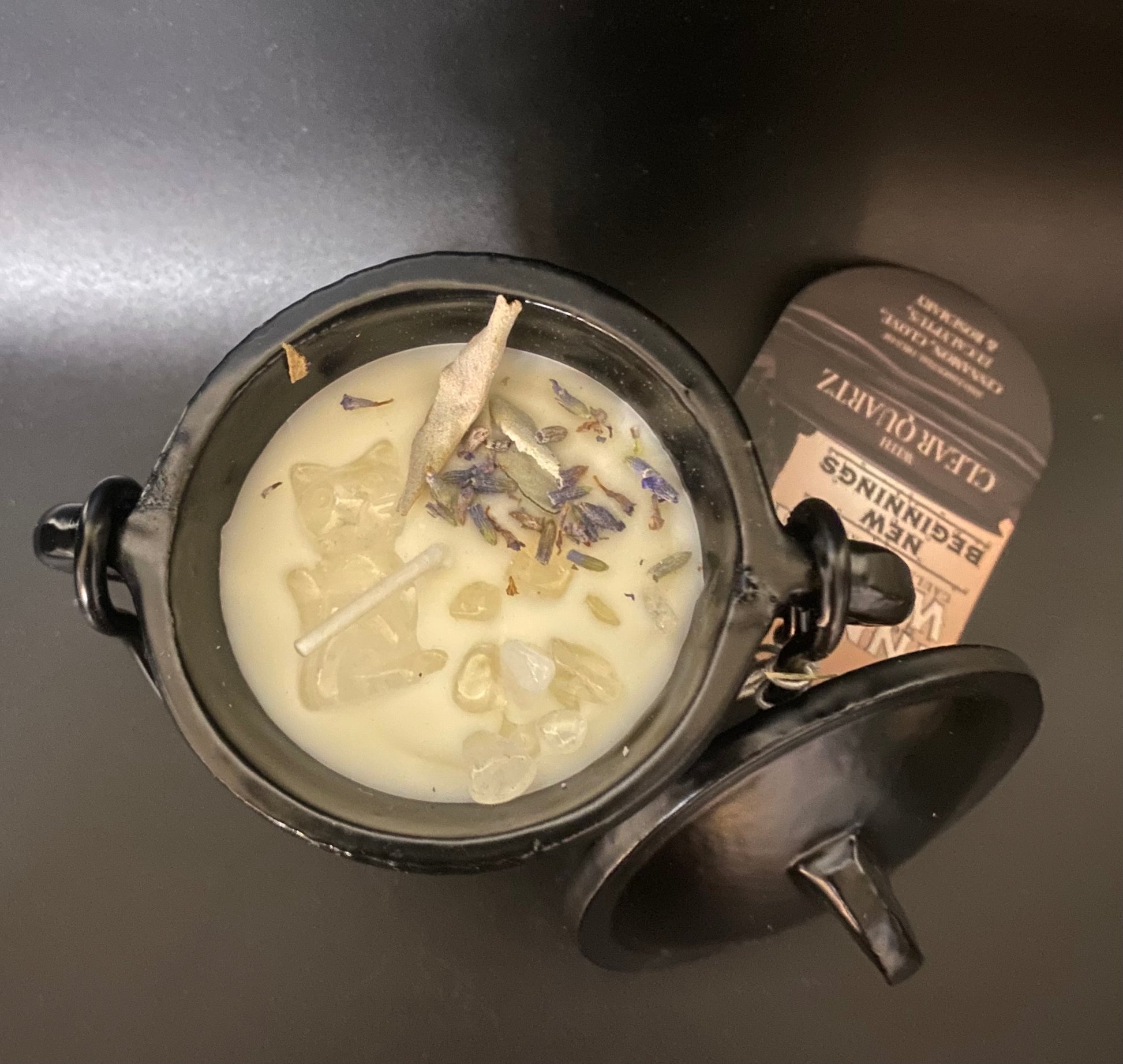 Candle with lavender buds in a cauldron on a dark surface
