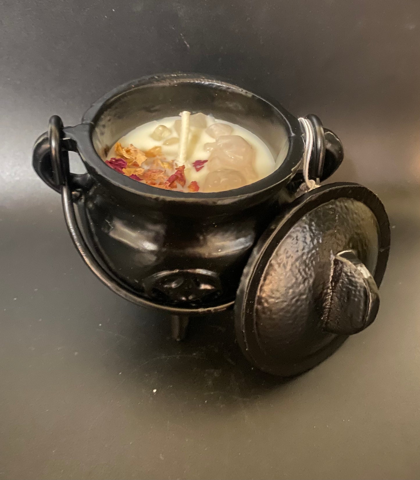 Black metal cauldron with a candle inside on a reflective surface