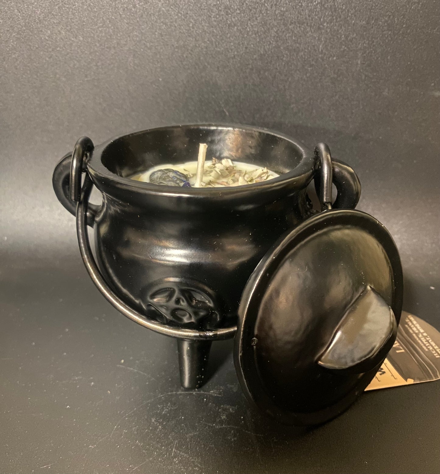 Black metal cauldron with lid on a gray background