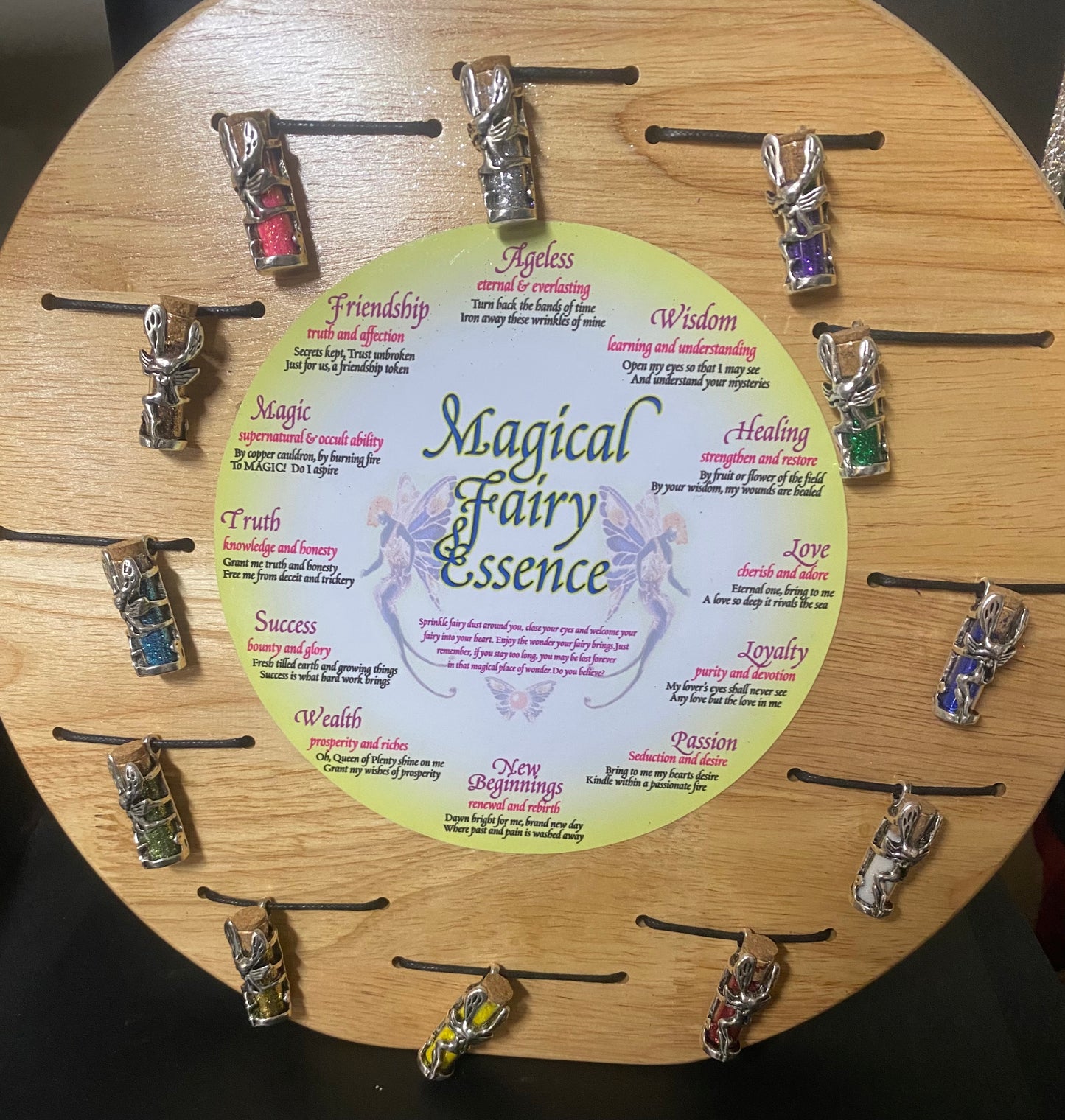Wooden display with 'Magical Fairy Essence' pendants and descriptive card.