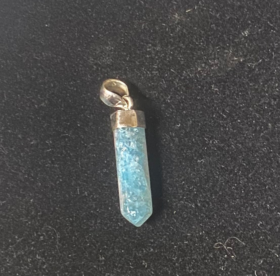 Blue crystal pendant with gold accent on a black background