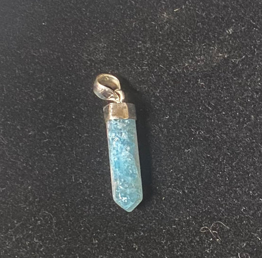 Blue crystal pendant with gold accent on a black background