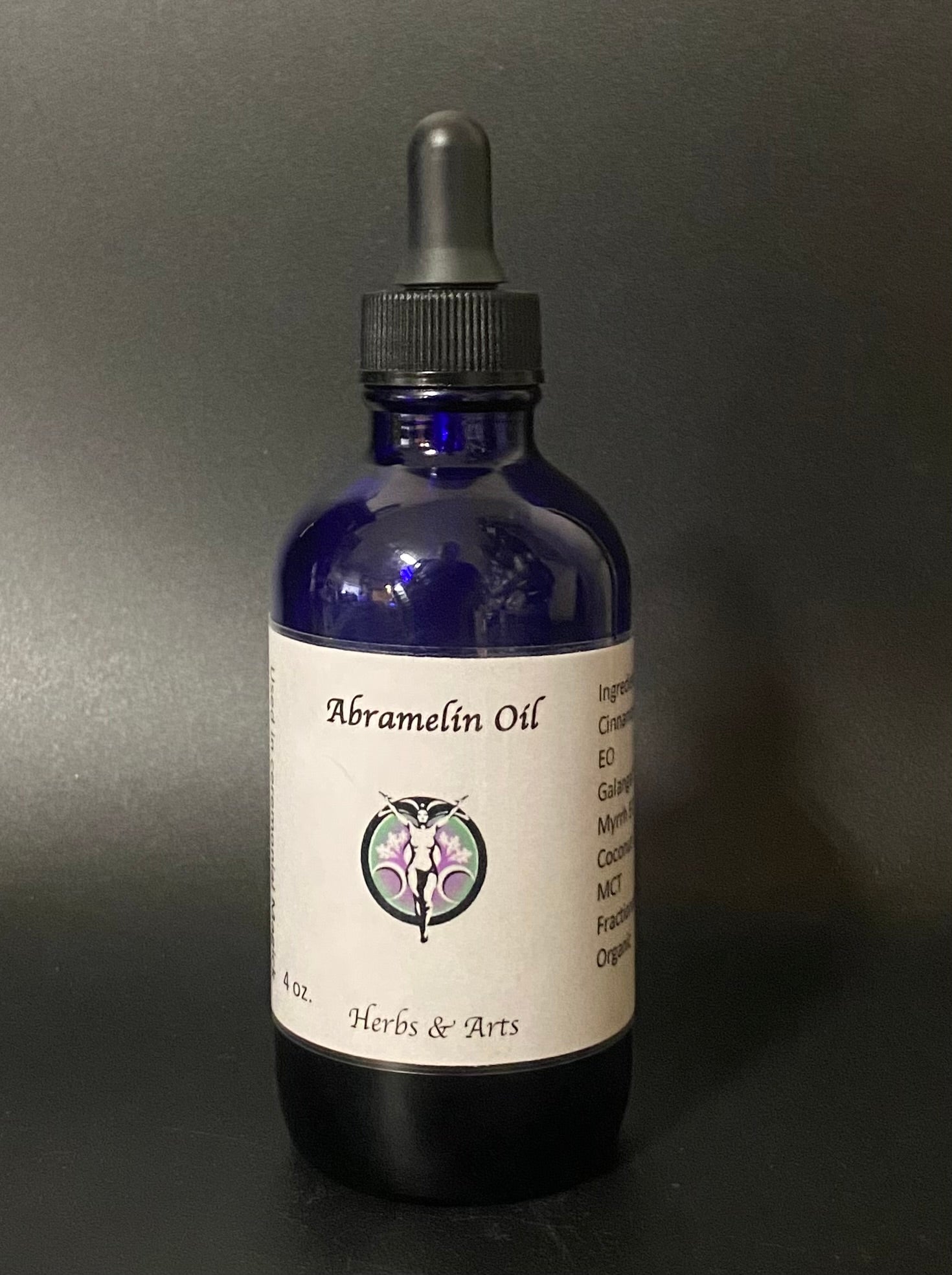 Bottle of Abramelin Oil with a label on a dark background