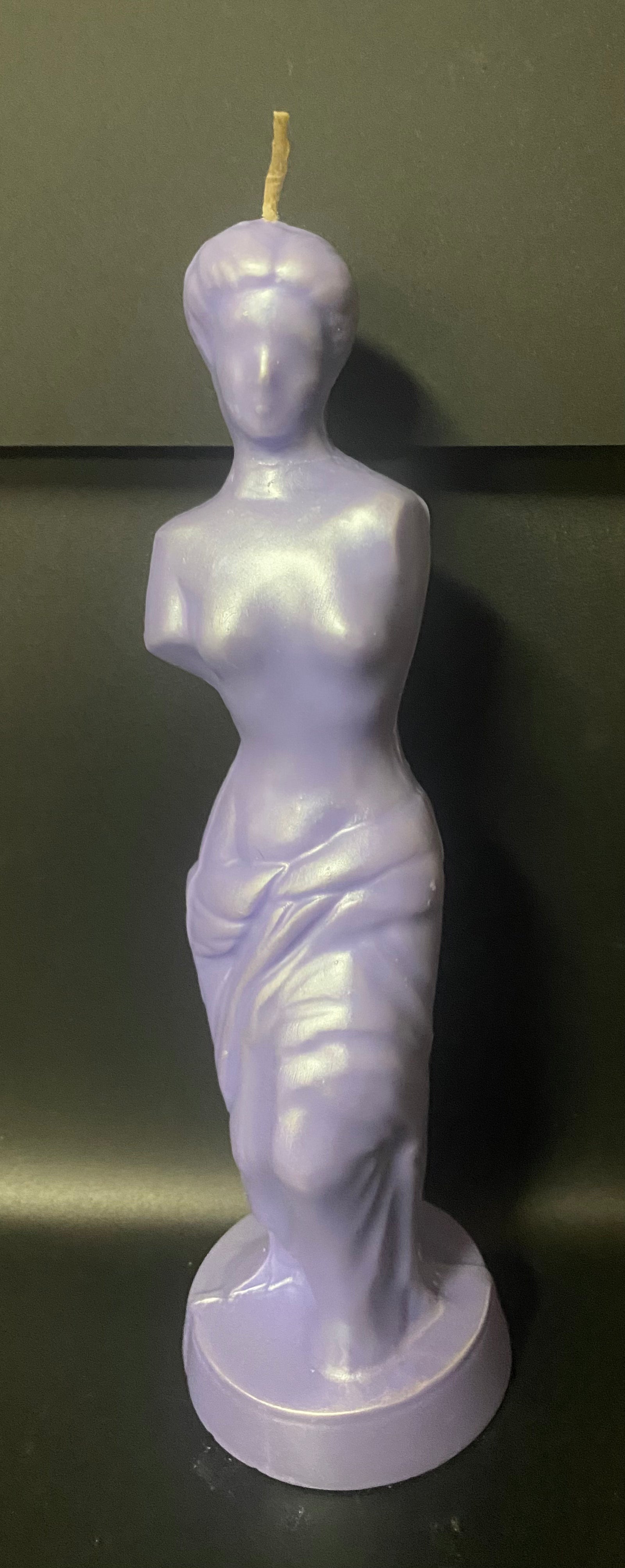 Candle shaped like a classical statue on a dark background