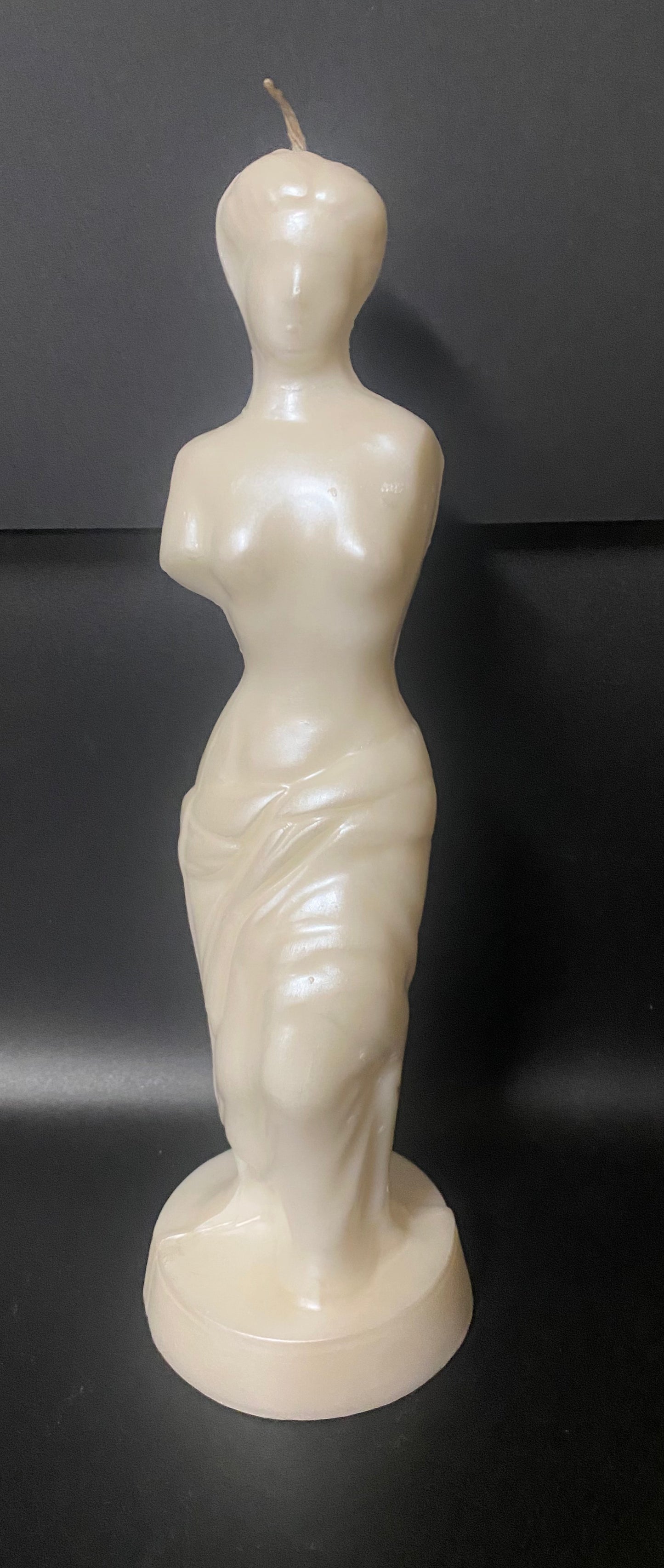 Candle shaped like a female figure on a black background