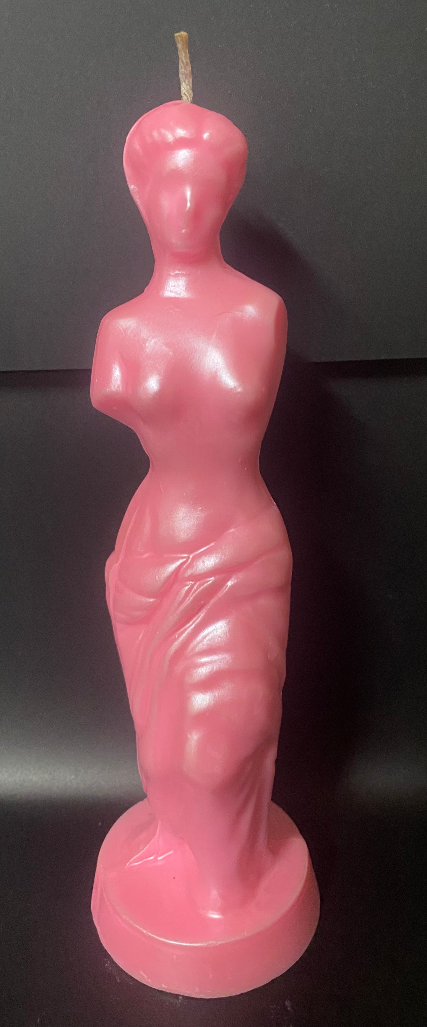 Pink candle shaped like a stylized female figure on a black background
