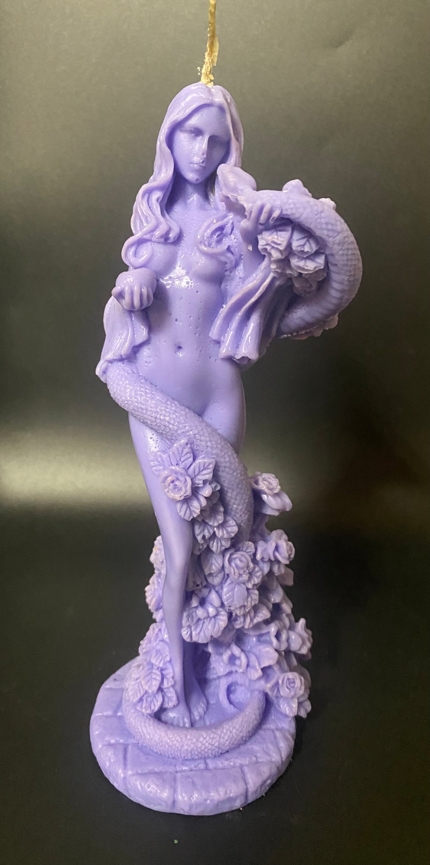 Purple statue of a woman holding flowers against a dark background