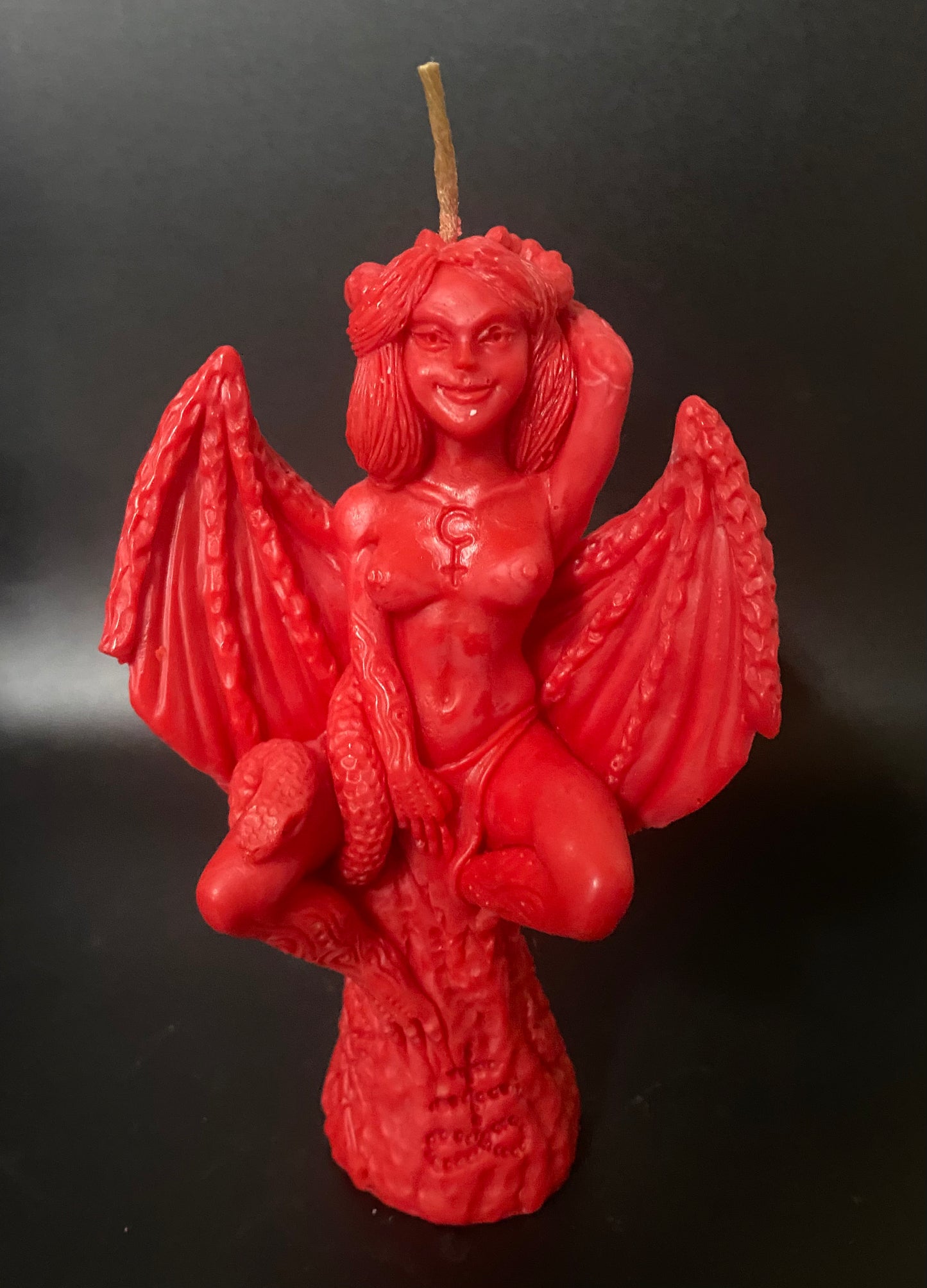 Red candle shaped like a winged creature on a black background