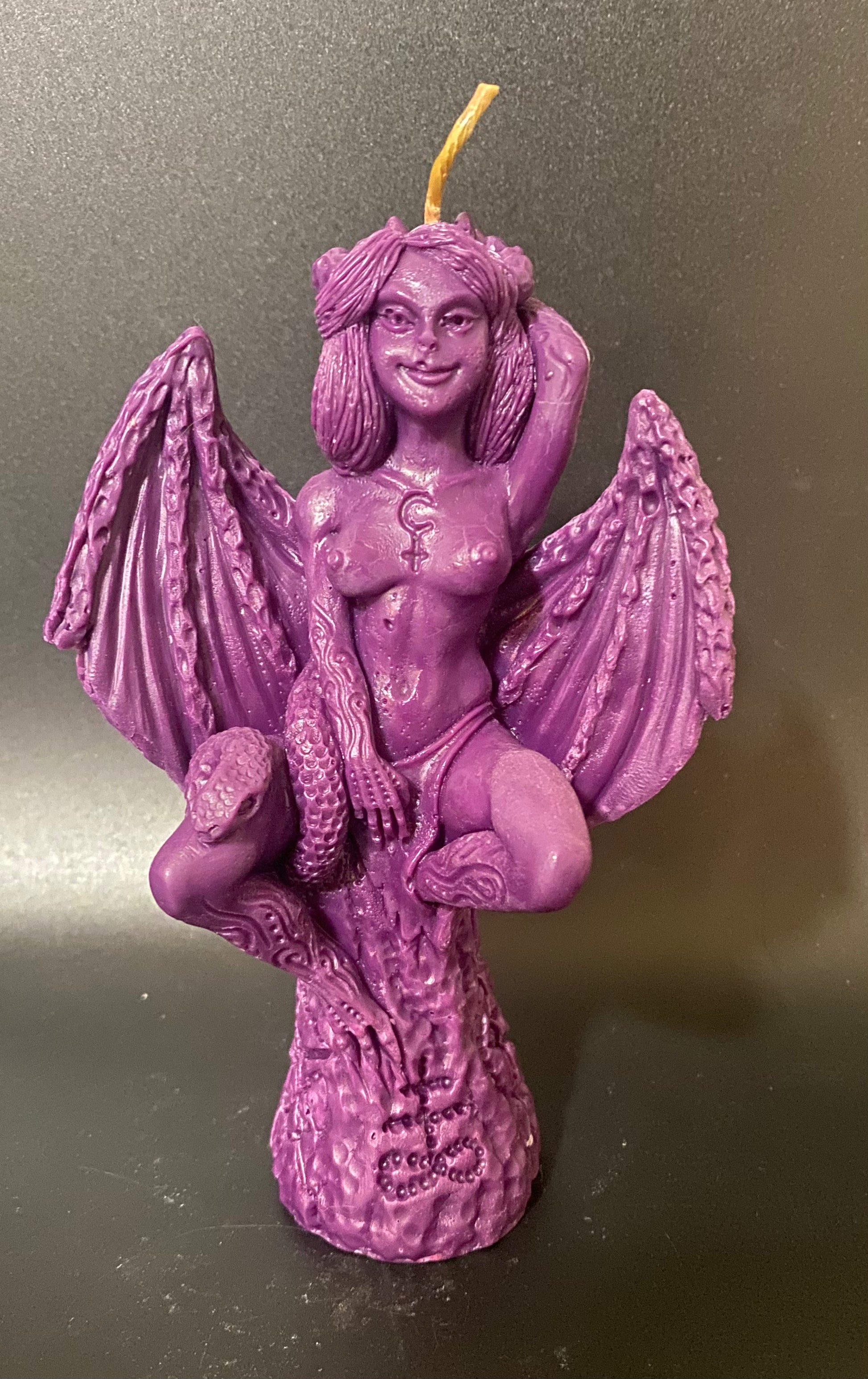 Purple candle with angelic figure on a dark background