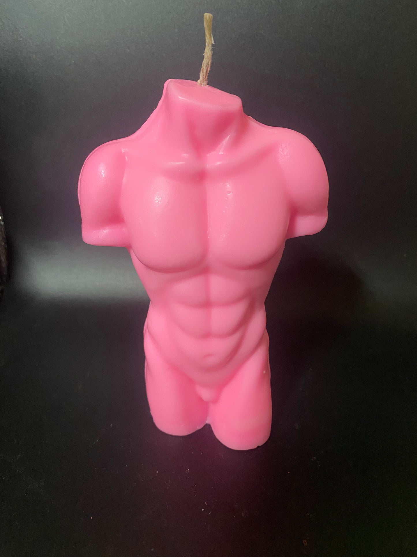 Pink muscular figure candle on a black background