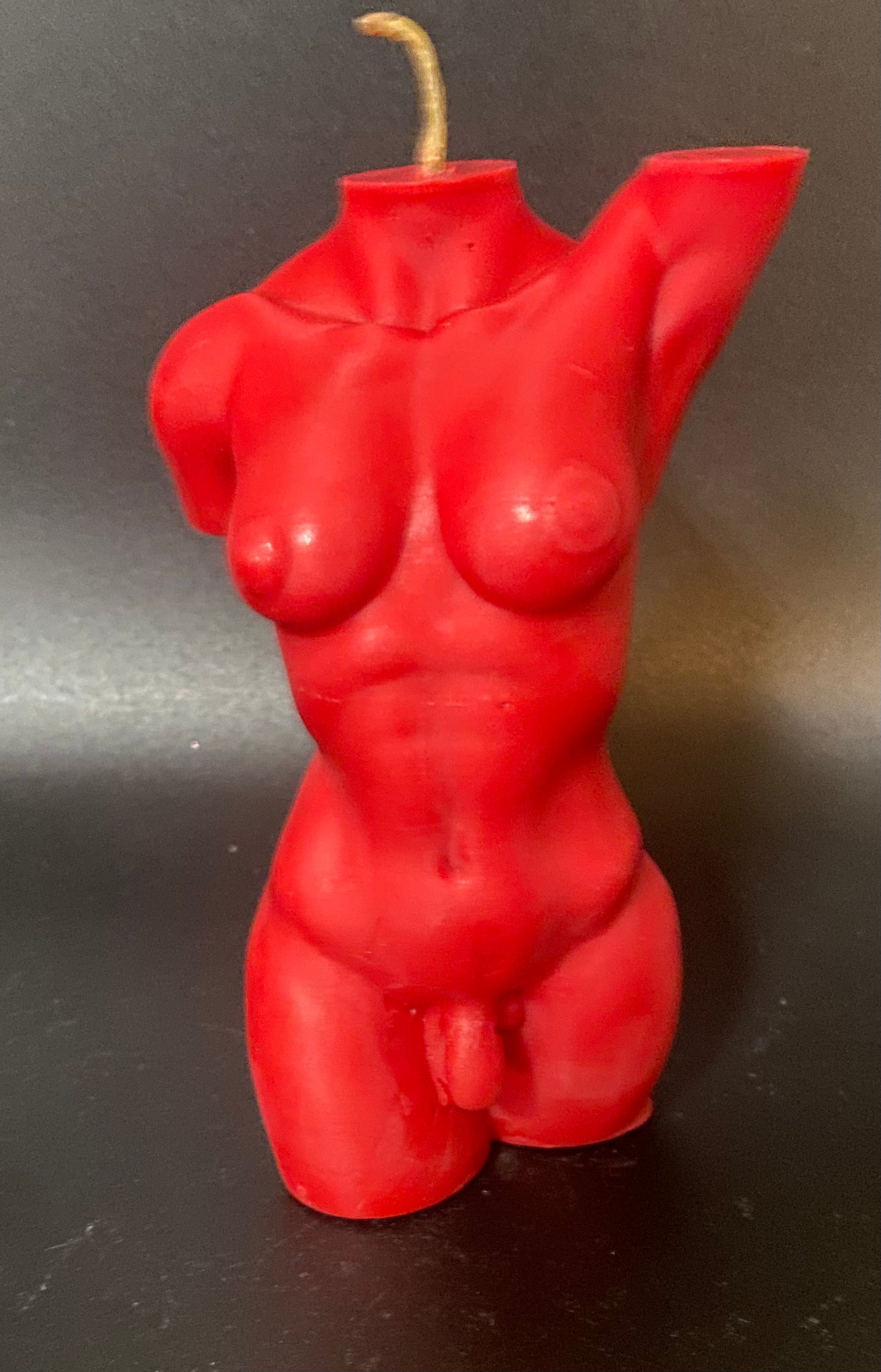 Red candle shaped like a female torso on a black background