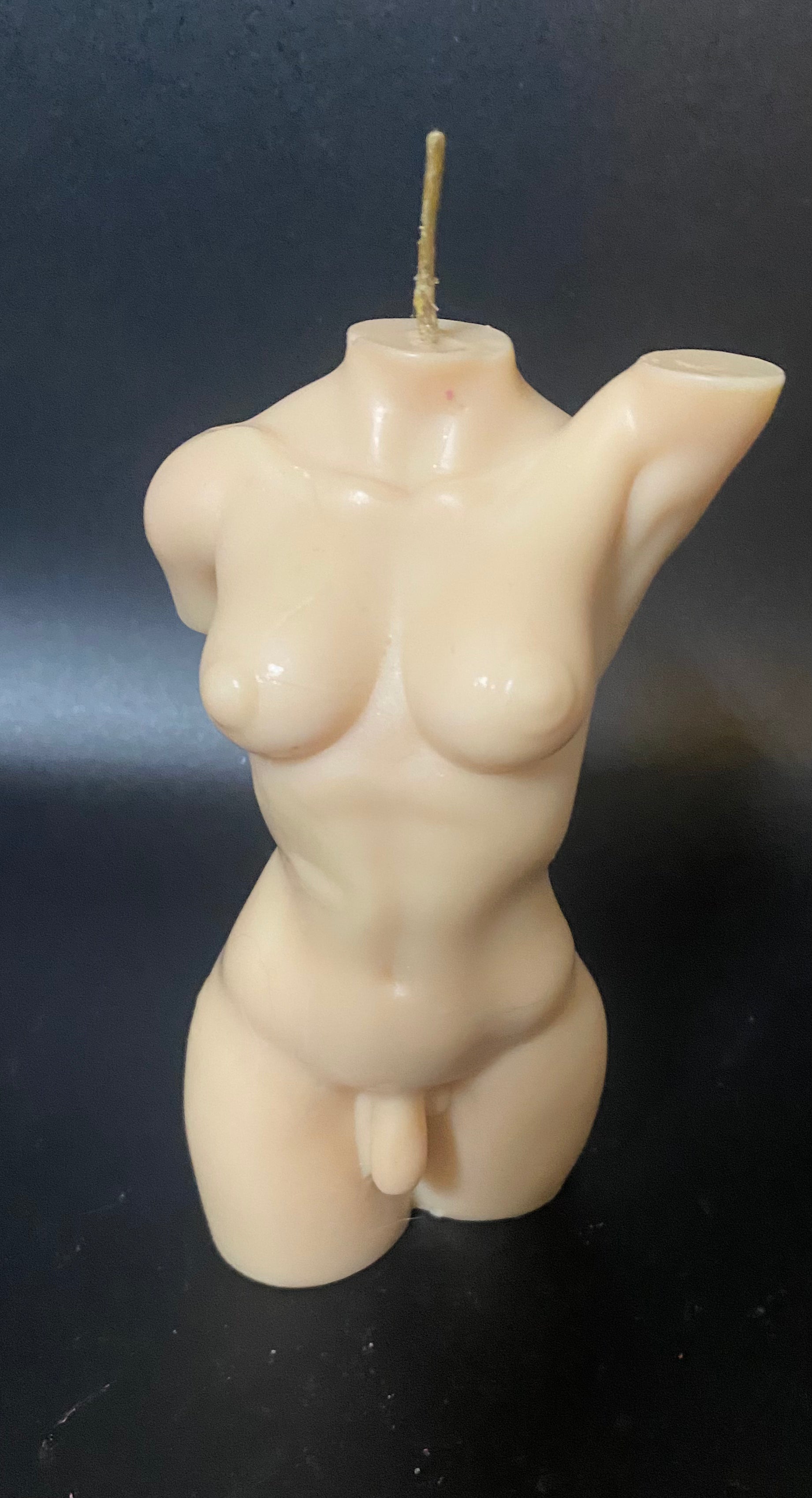 Candle shaped like a human torso on a dark background