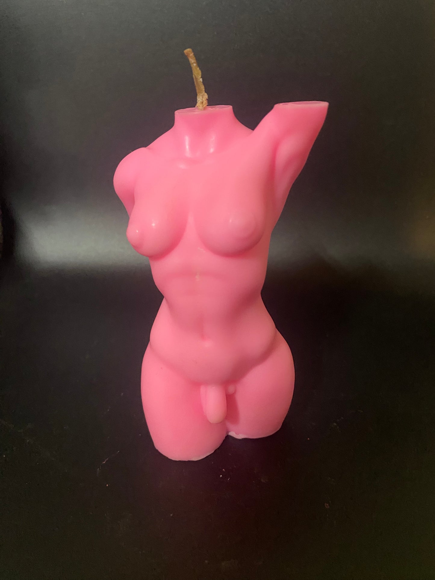 Pink candle shaped like a female torso on a black background
