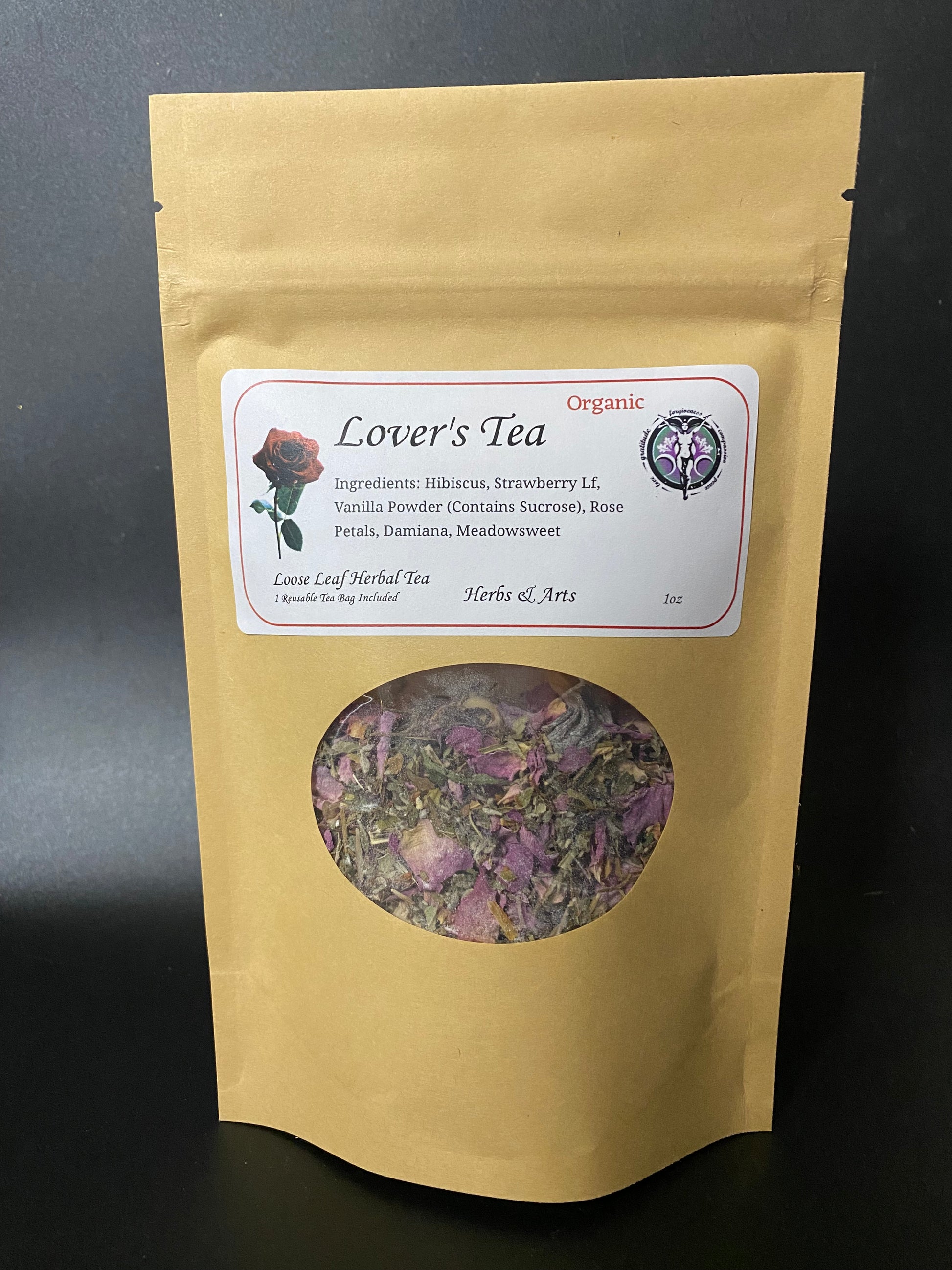 A stand-up kraft paper pouch of Lover's Tea herbal tea with a clear circular window showing dried flowers and leaves inside. The front label reads 'Lover's Tea' and includes an organic seal.