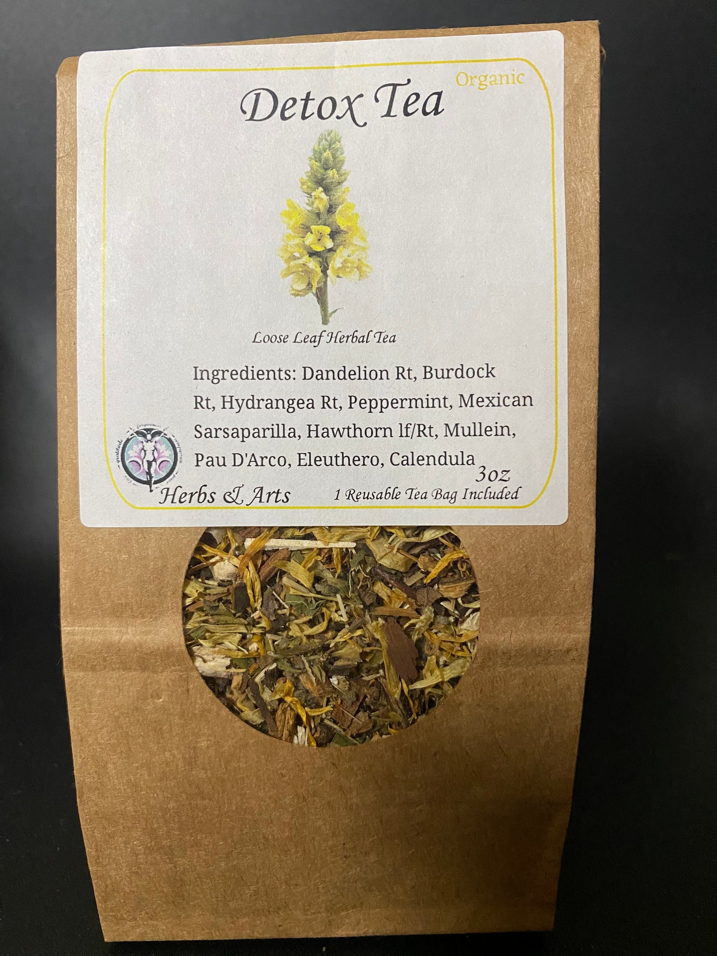 A stand-up kraft paper pouch of Detox Tea with a white label and a circular window showing the dried herbal tea inside, photographed against a dark background.