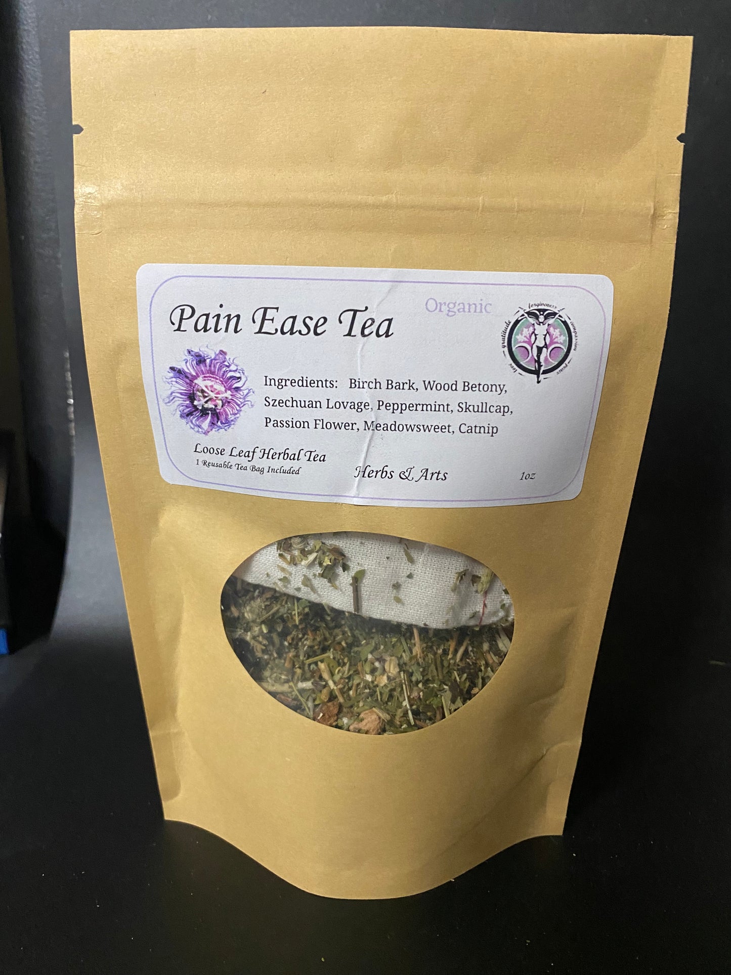 A stand-up kraft paper pouch of Pain Ease Tea with a white label and a circular window showing loose leaf herbal tea inside, photographed against a dark background.