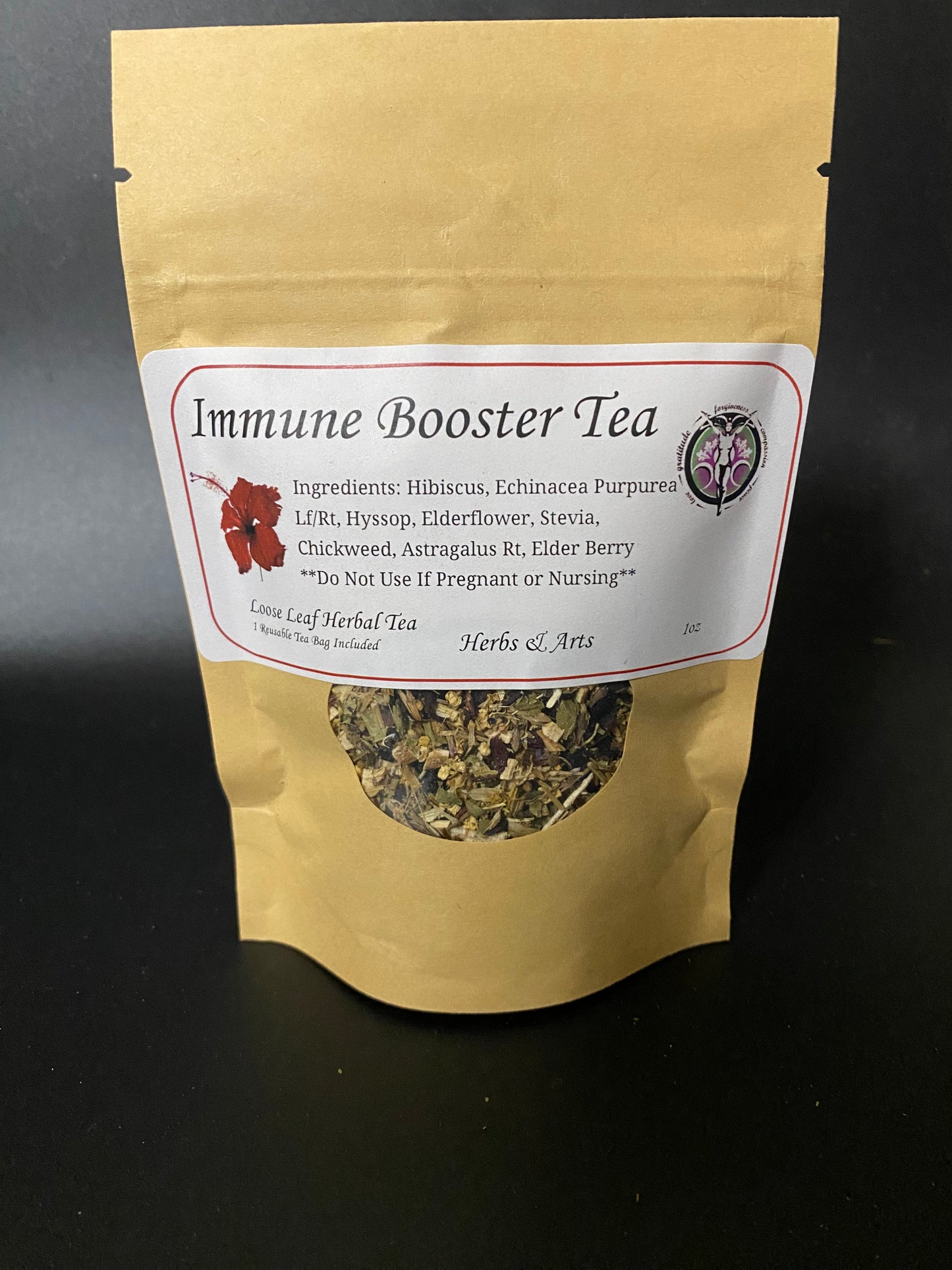 A stand-up kraft paper pouch of Immune Booster Tea with a white label and a circular window showing the dried herbal tea inside, photographed against a dark background.