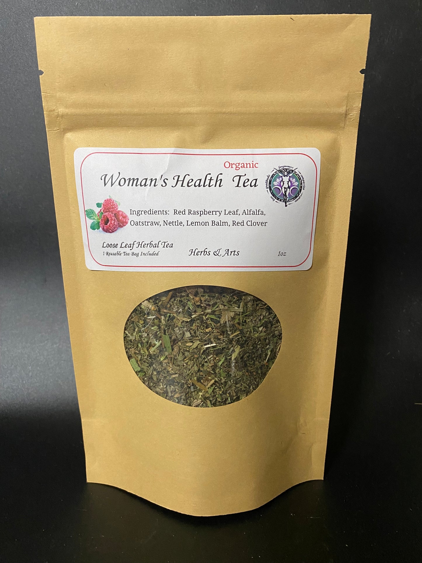 A stand-up kraft paper pouch of Woman's Health Tea with a white label and a circular window showing loose leaf herbal tea inside, photographed against a dark background.