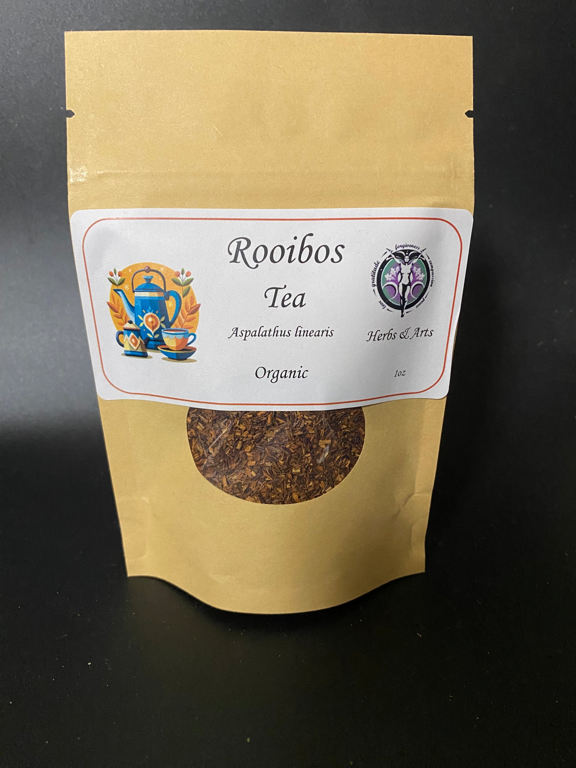 A stand-up kraft paper pouch of Rooibos Tea with a white label and a circular window showing loose leaf herbal tea inside, photographed against a dark background.