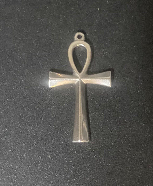 A polished silver-toned metal ankh pendant with a flat, geometric design, shown on a dark textured background.