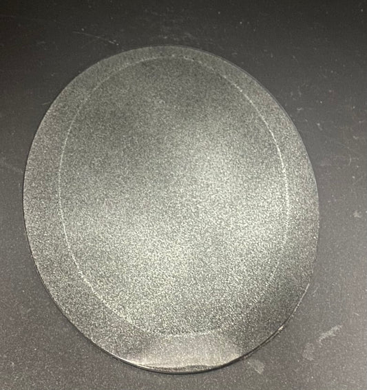 A oval, textured gray glass scrying mirror shown from above on a dark gray surface.