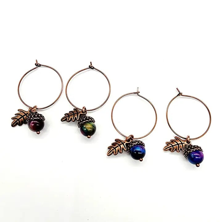 Set of four earrings with acorn and leaf designs on a white background
