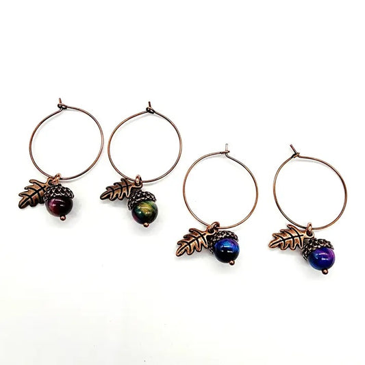 Set of four earrings with acorn and leaf designs on a white background
