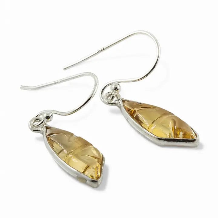 Pair of silver earrings with teardrop-shaped citrine stones on a white background