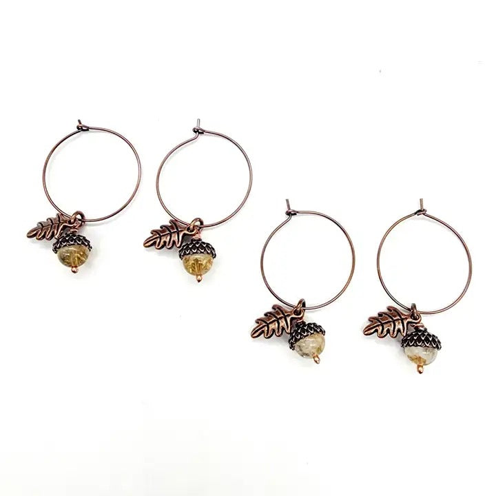 Set of four earrings with leaf and acorn designs on a white background