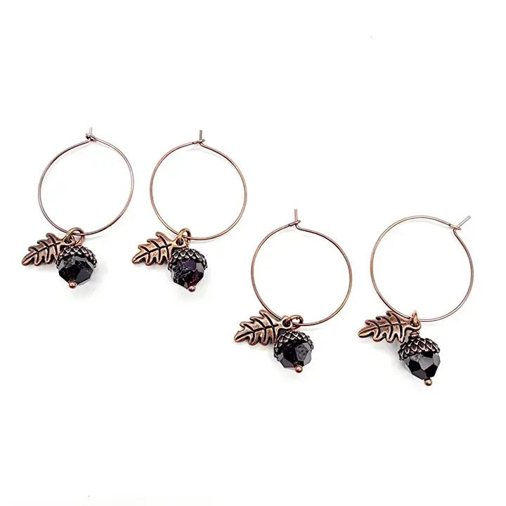 Four earrings with leaf and black bead designs on a white background