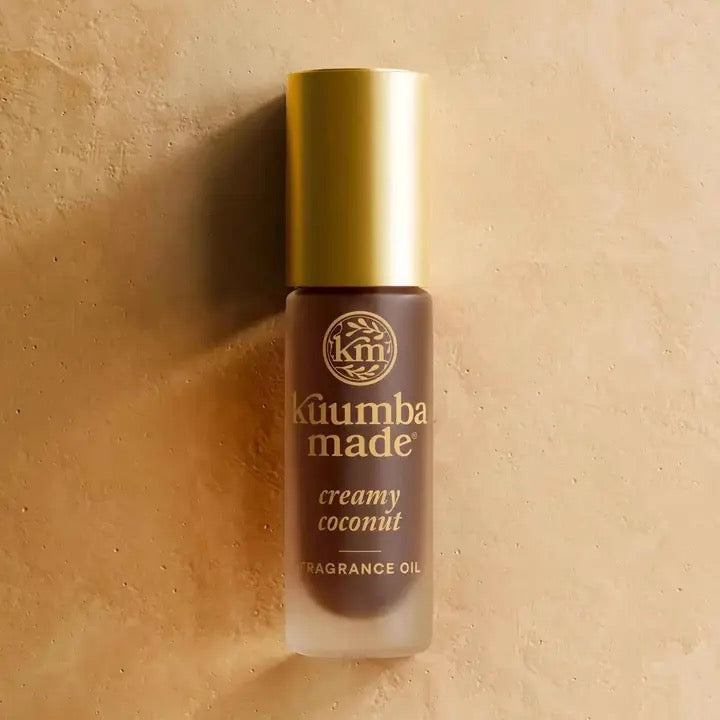 Kuumba Made creamy coconut fragrance oil bottle on a beige background