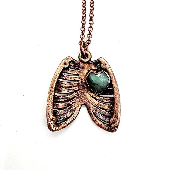 Bronze pendant with a green gemstone on a white background