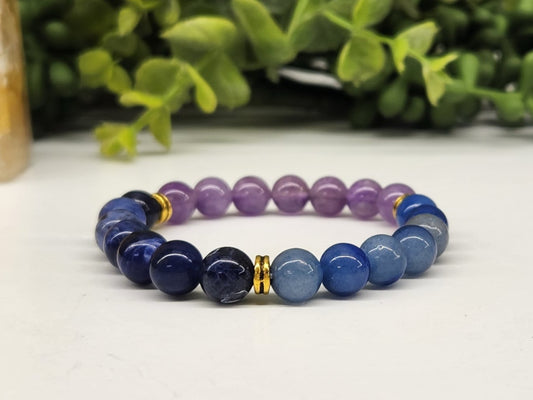Multicolored beaded bracelet on a white surface with greenery in the background
