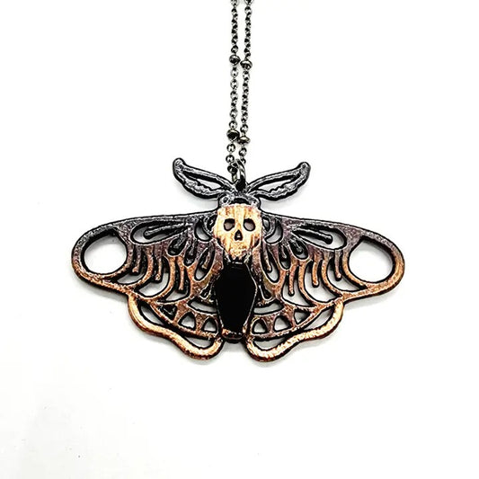 Moth-shaped pendant with skull design on a white background