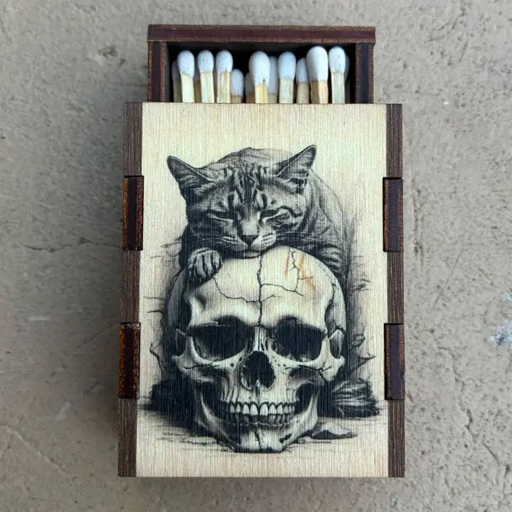 Matches with a wooden box featuring an illustration of a cat on top of a skull.