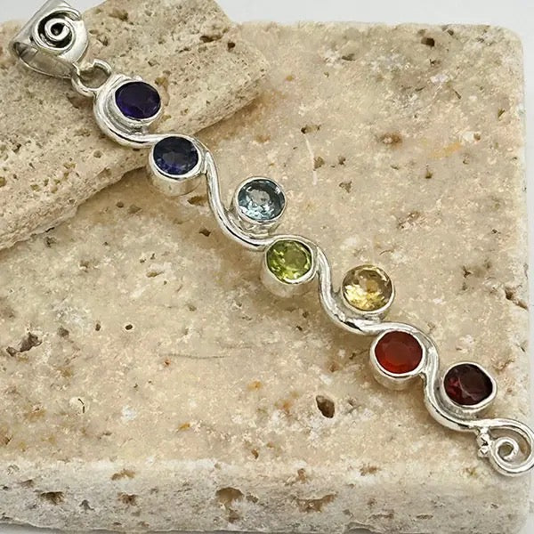 Silver pendant with colorful gemstones on a stone surface