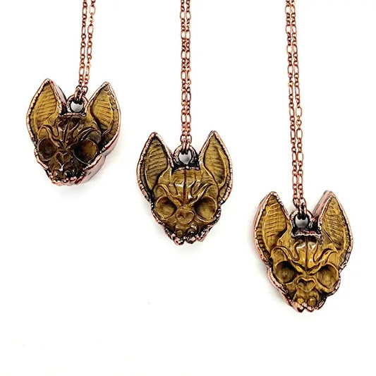 Three gold cat-shaped pendants on chains against a white background
