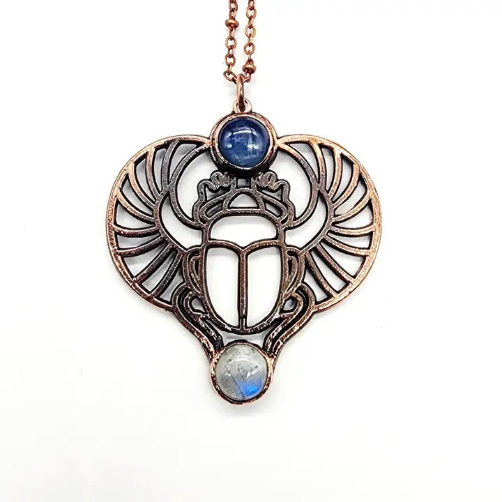 Decorative necklace with winged heart design and gemstones on a white background