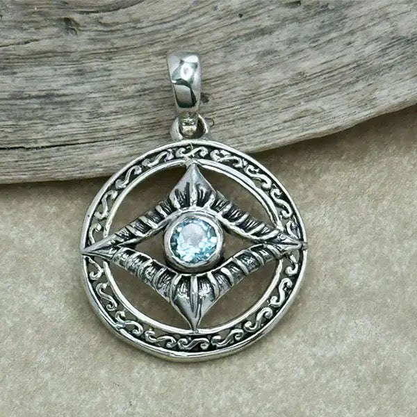 Silver pendant with a blue gemstone on a wooden surface