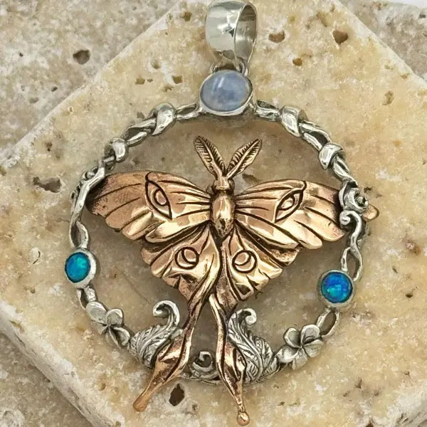 Butterfly pendant with silver and bronze details on a stone surface