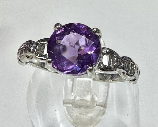 Silver ring with a purple gemstone on a white background