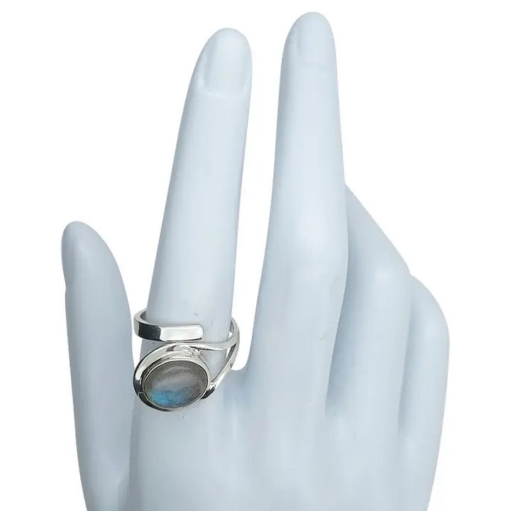 Silver ring with a blue gemstone on a mannequin hand against a white background