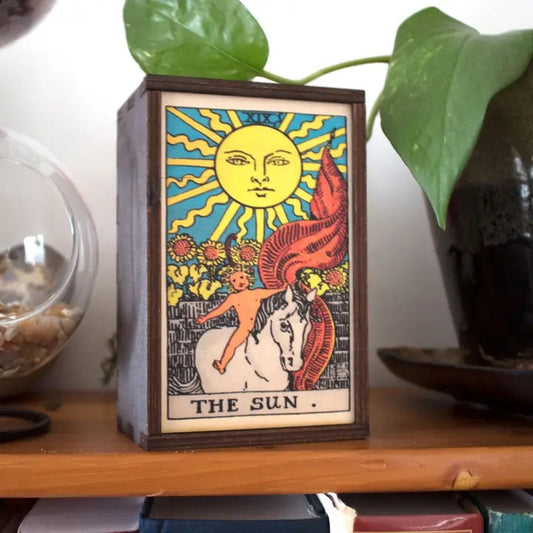 Decorative box with 'The Sun' tarot card design on a wooden surface.