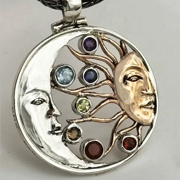 Pendant with faces and gemstones on a gray background