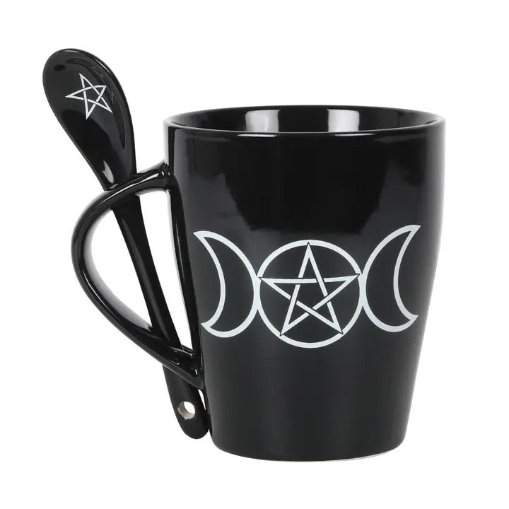 Black mug with white pentagram and moon phases design, accompanied by a matching spoon on a white background.