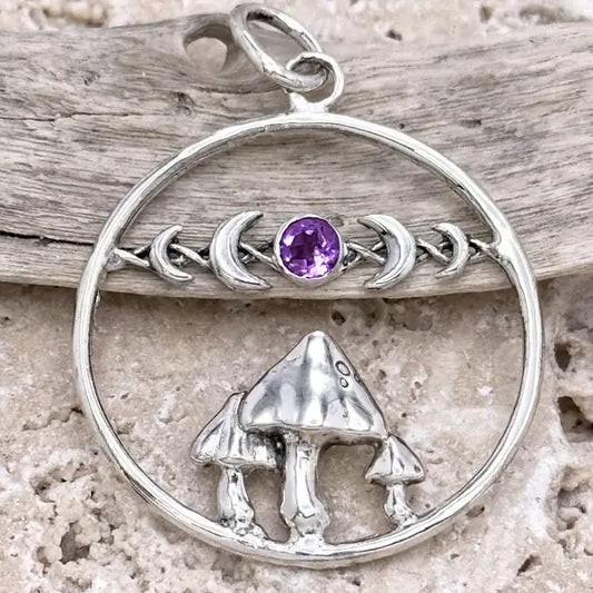 Silver pendant with mushrooms and a purple gemstone on a wooden background