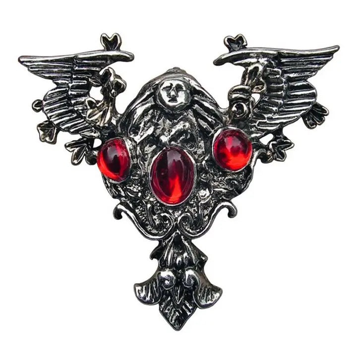 Decorative brooch with red gemstones and wings on a white background